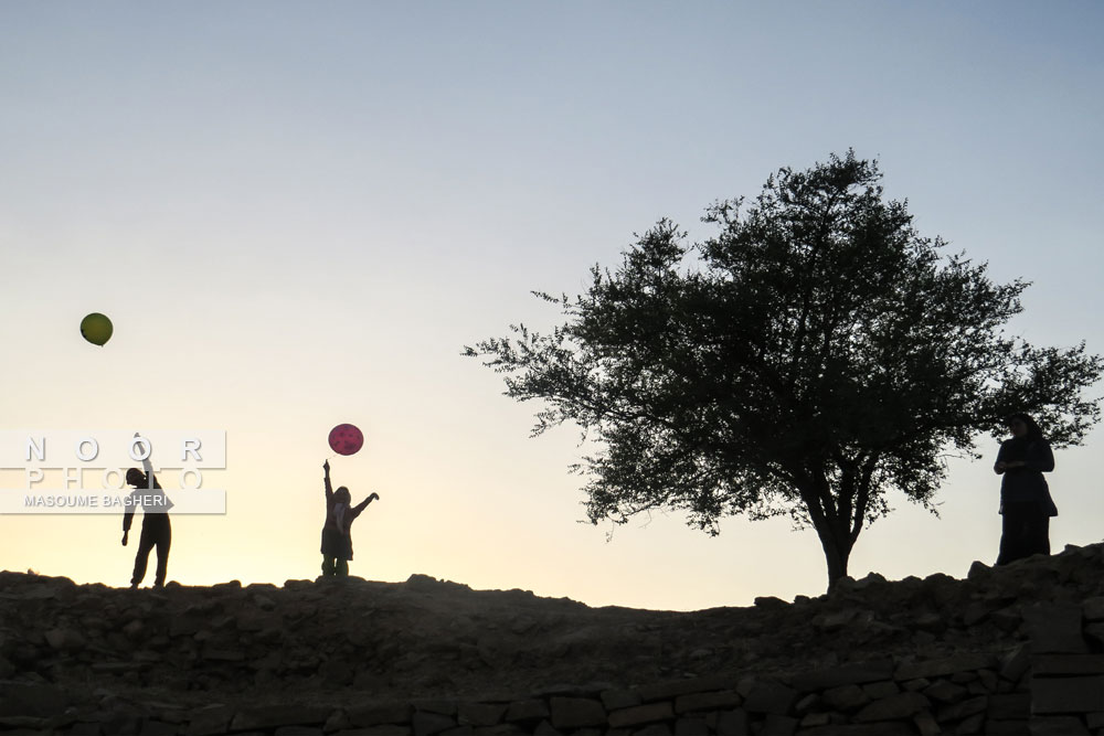 کودکان درآتشکده باستانی مسجدسلیمان ،زیردرخت کنار،درحال بادکنک بازی هستند